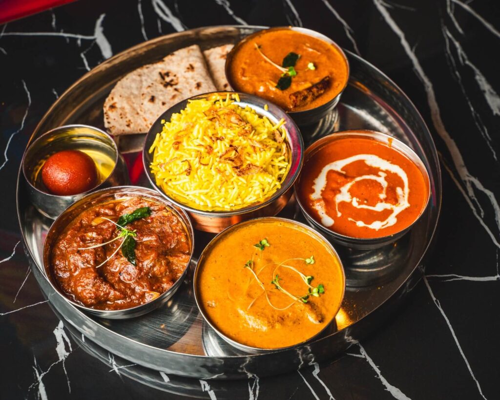 Lunch time thali served with Popadom, Samosa with three curries, rice, chapathi and Sweet